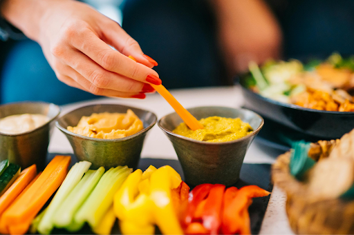 Fresh vegetable platter with dips and people serving themselves