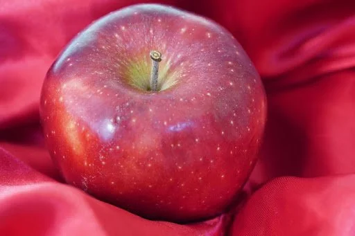 Red Delicious apple with deep red skin on a red background