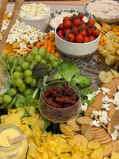 Cheese board with grapes, tomatoes, nuts, and assorted cheeses