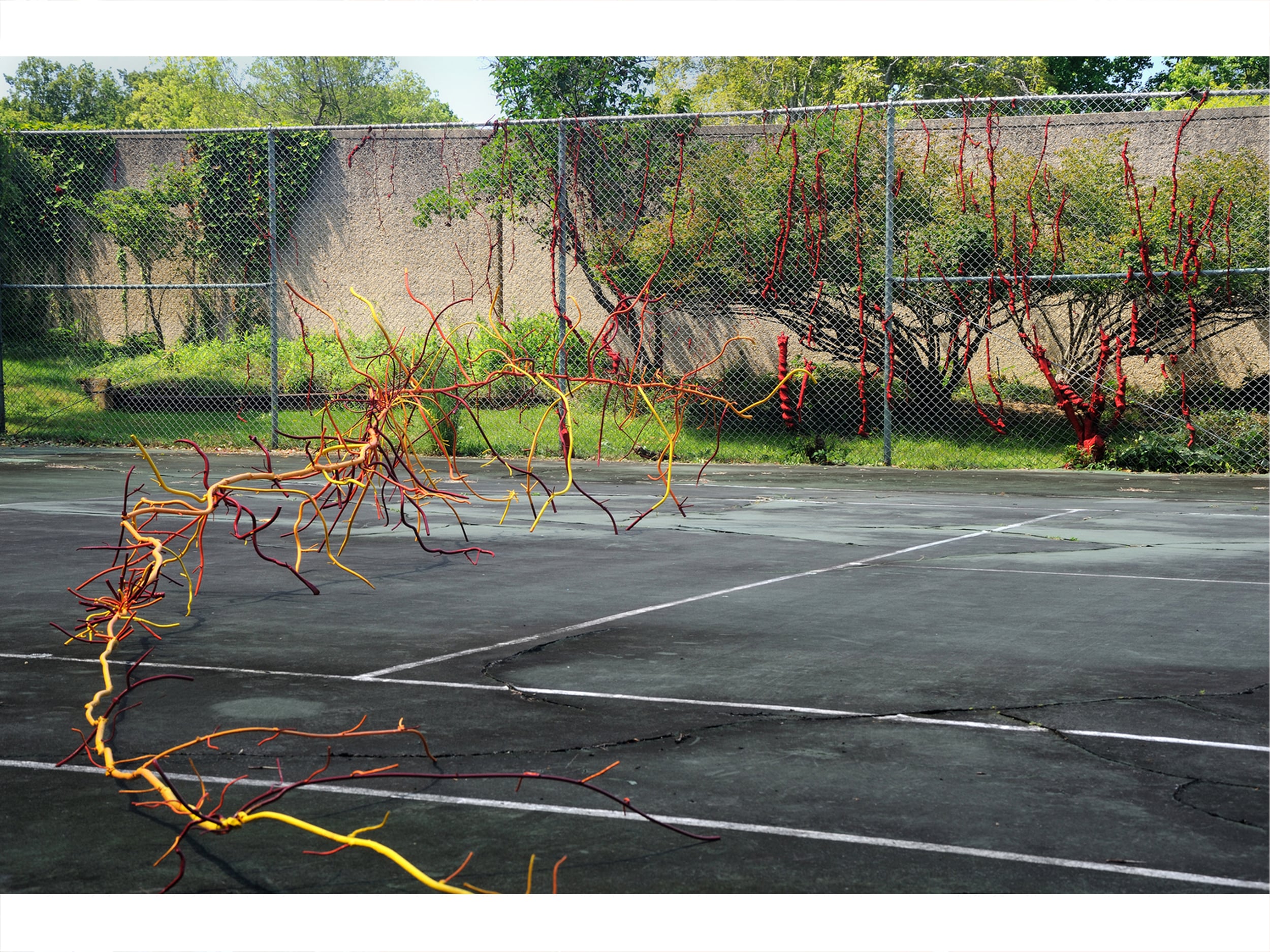 A colorful metal ROOT sculpture along the width of the tennis court