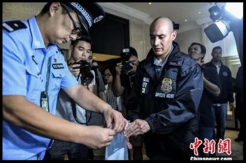 A Chinese police officer hands over a U.S. fugitive's personal belongs to the U.S. police. (File photo/China News Service)