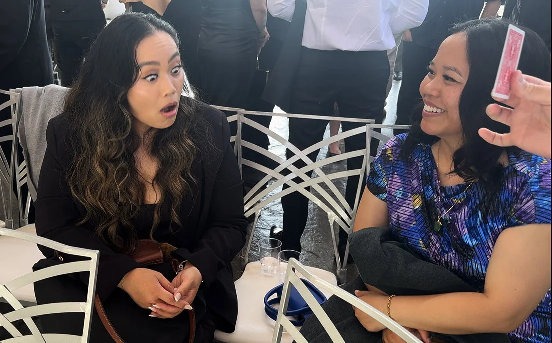 Two guests at a Los Angeles wedding cocktail hour reacting with genuine astonishment to Christopher Moro's close-up magic