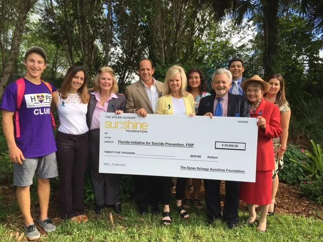 HOPE Club Members, FISP Board Member and Debbie and David Schopp holding donation check inside the Markham Park Butterfly Garden created in honor of Dylan Schopp.