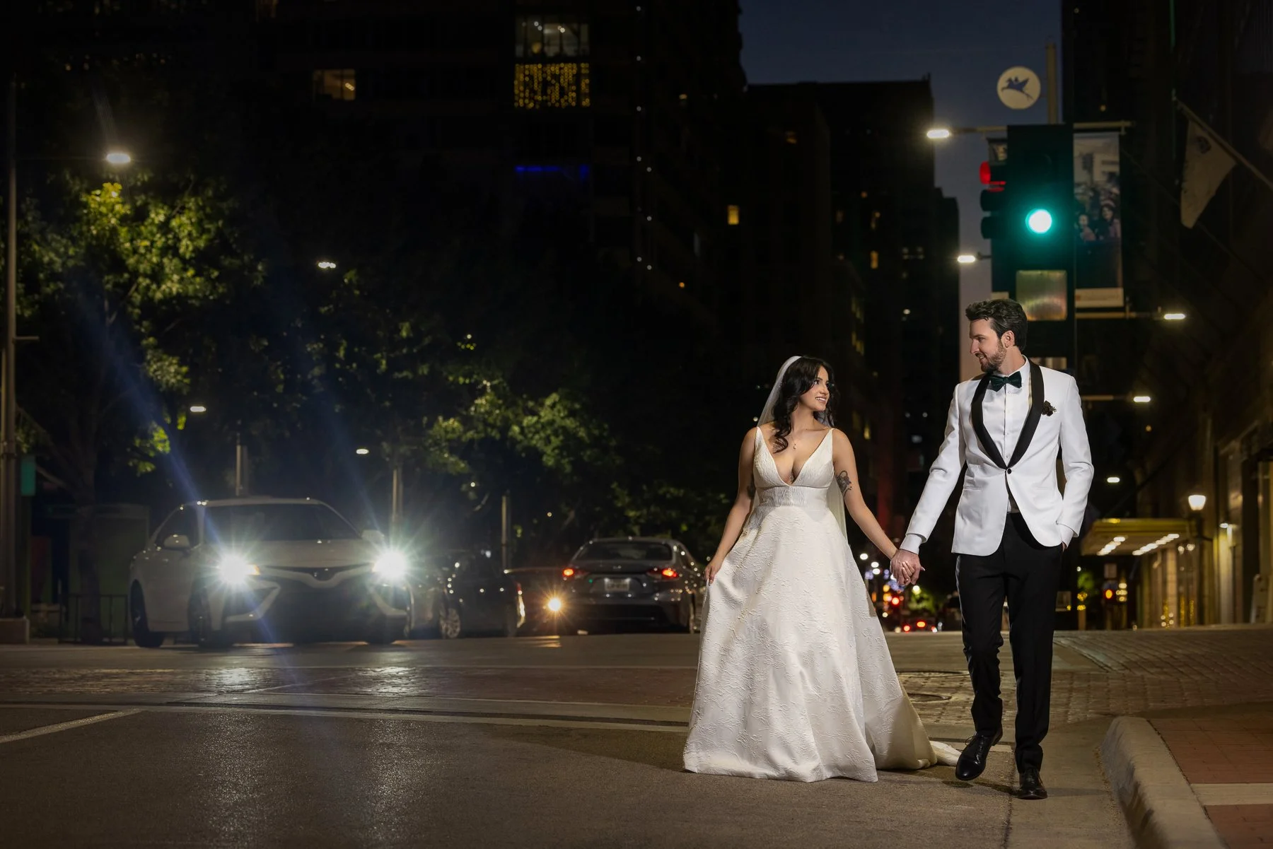 Bride and groom walking through downtown Dallas at night with cinematic wedding photography