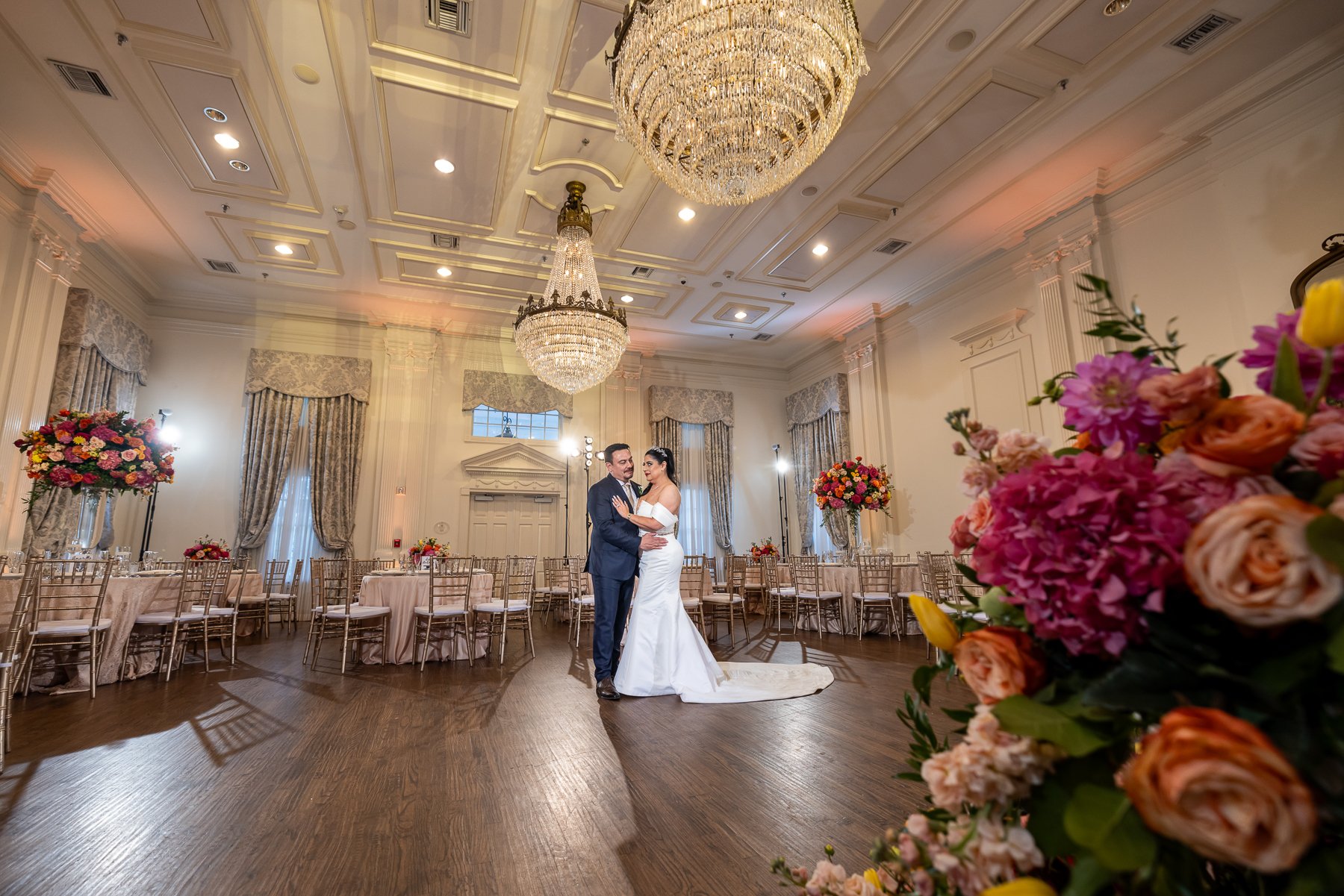 Bride and groom inside their Arlington Hall wedding reception in Dallas surrounded by colorful floral decor.