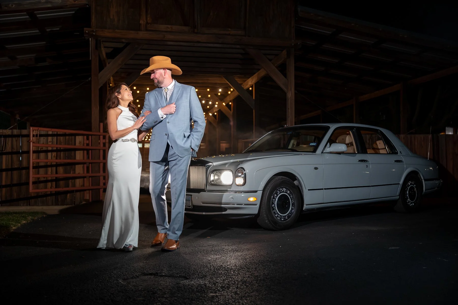 Newlywed couple posing beside a Rolls-Royce at Lucky Spur Ranch in Justin, TX.