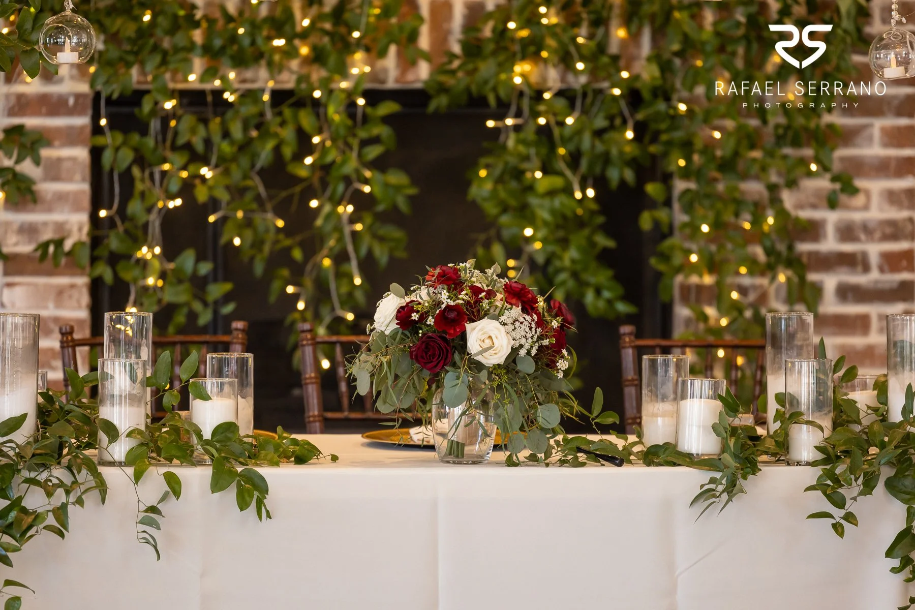 Wedding reception table decorated with greenery, candles, and a floral centerpiece.