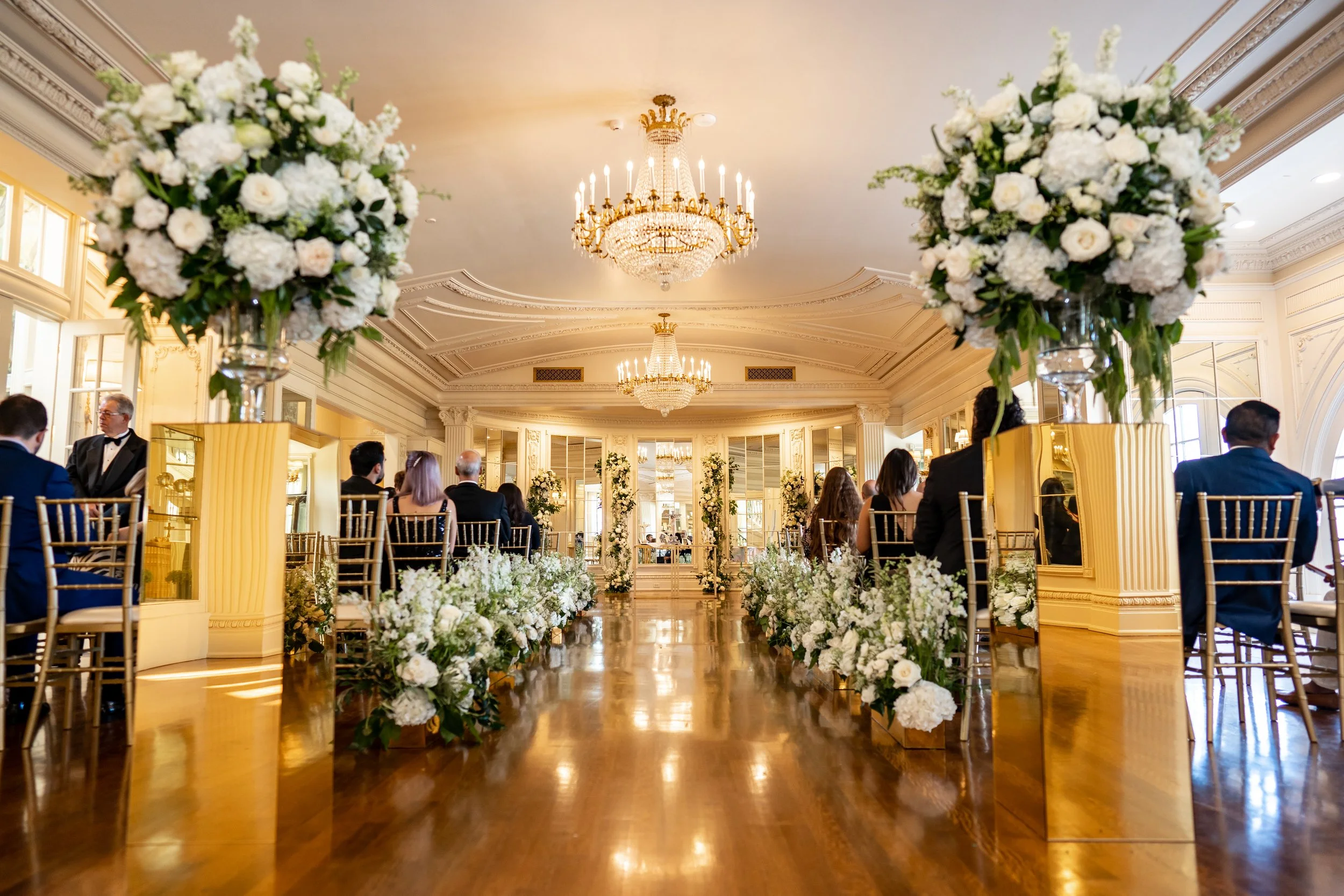 Elegant Dallas wedding ceremony decorated with white and green floral arrangements and gold details.