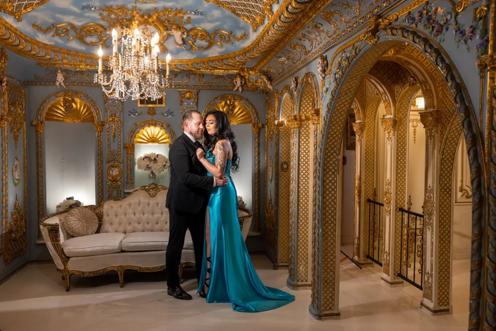 Couple standing beneath a chandelier in a blue-and-gold room at Dallas Dreamhaus.