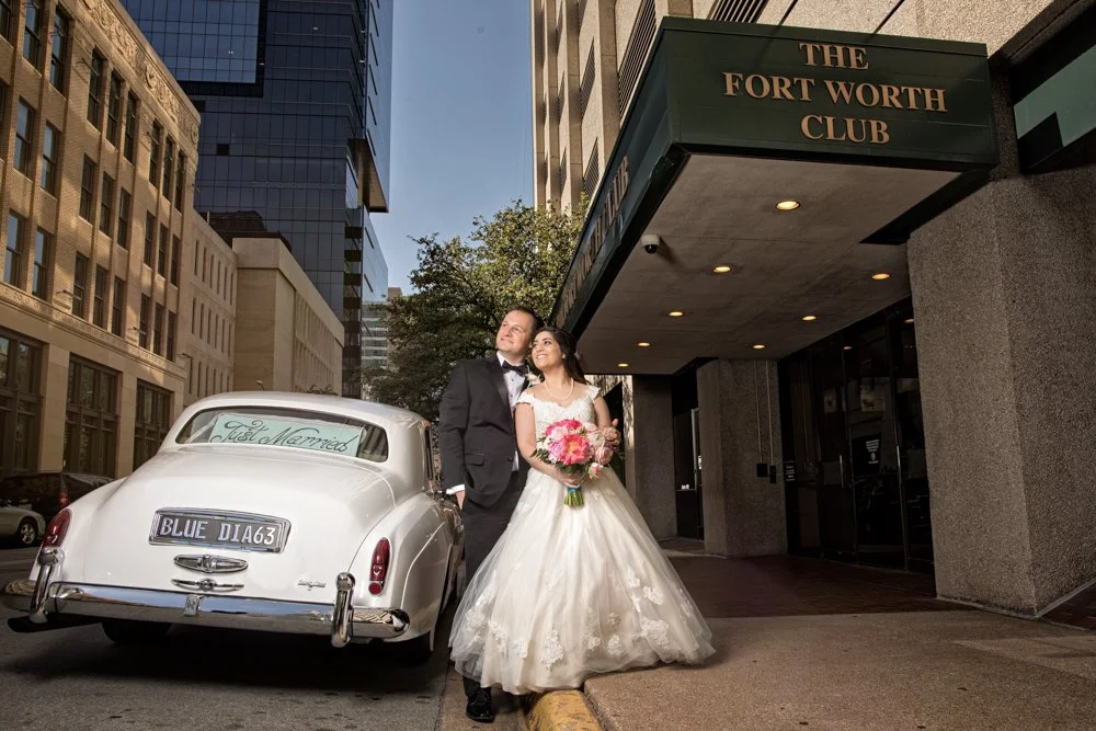 Bride and groom walking together inside The Fort Worth Club wedding venue with mirrored hallways and historic architectural details