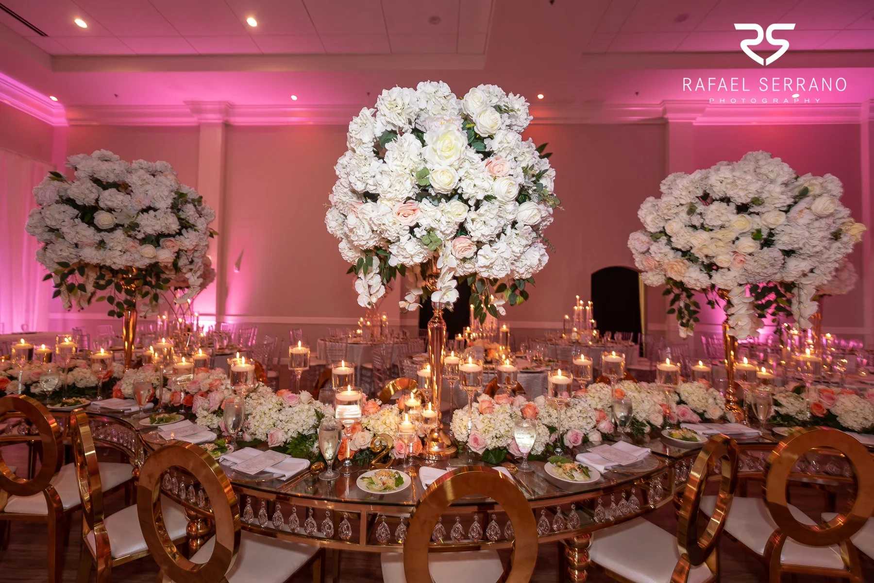Elegant Dallas wedding reception decorated with floral centerpieces, candles, and pink lighting.