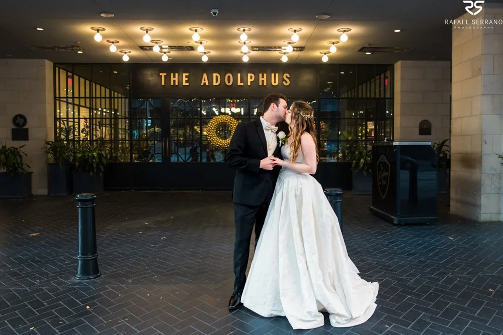 McKenna and Chris kissing beneath The Adolphus entrance sign.