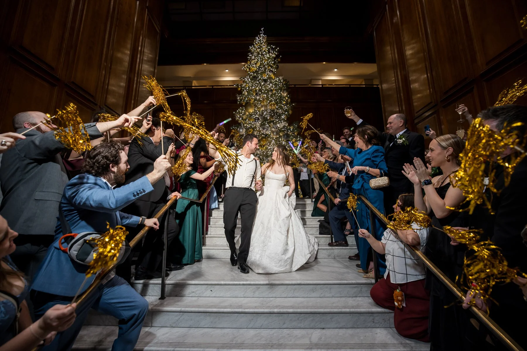 Bride and groom celebrating with guests on the staircase during their wedding exit at The Adolphus Hotel