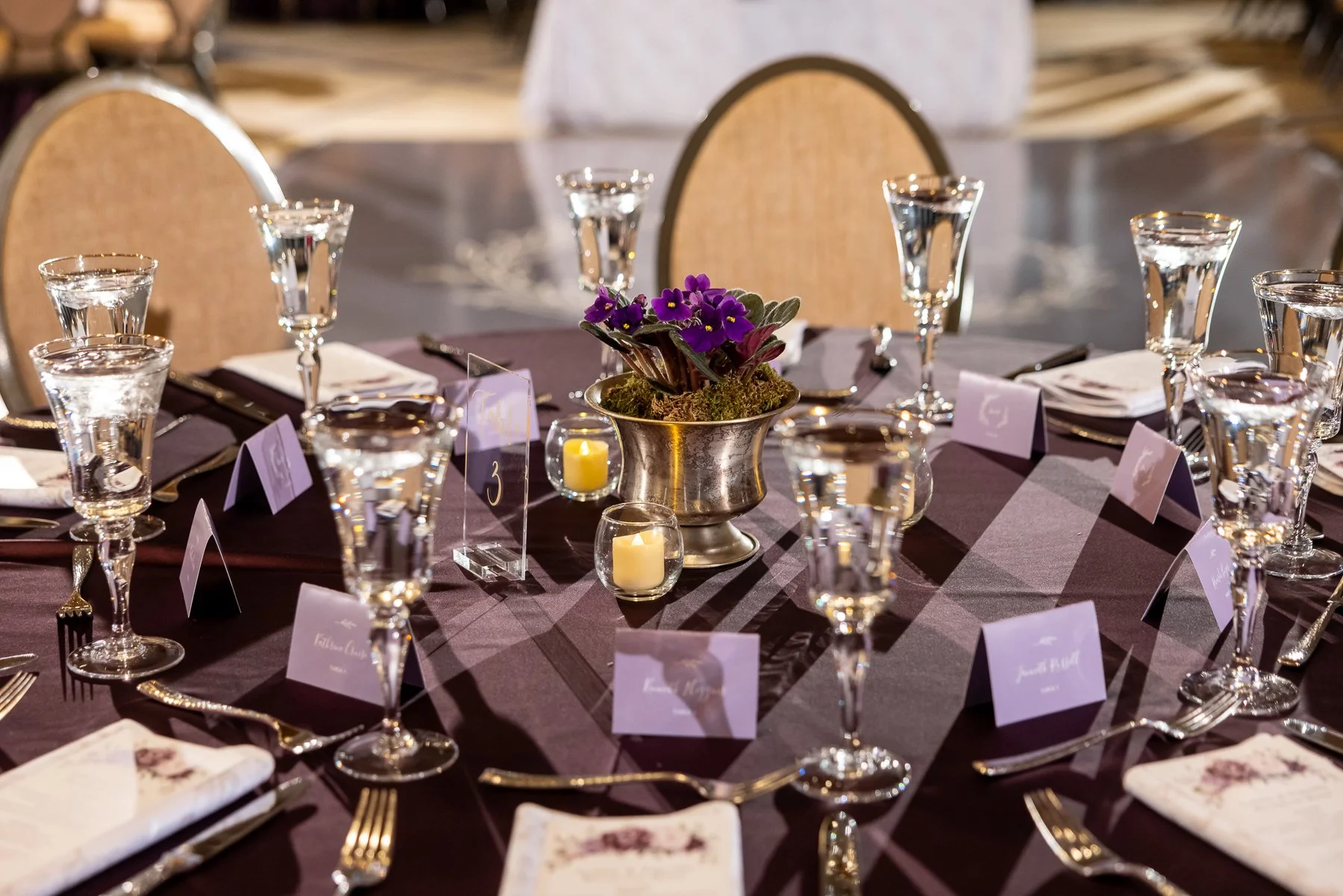 Purple floral arrangements and candlelit tables during a wedding reception at Omni Dallas Hotel
