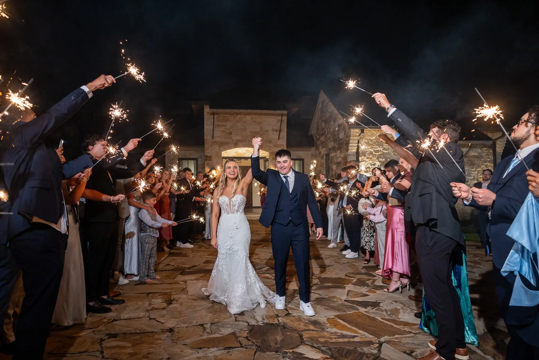 Bride and groom walking through a sparkler exit surrounded by family and friends at The Laurel in Grapevine, Texas.