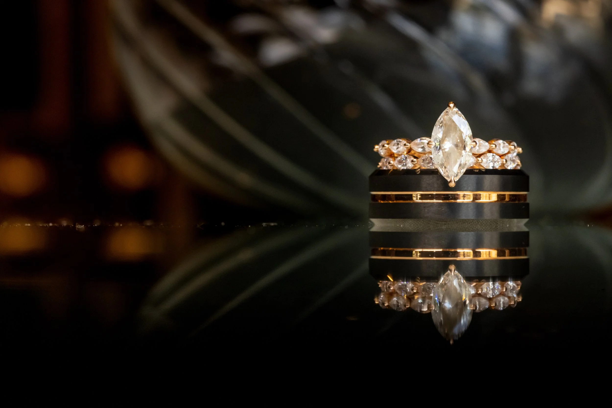 Marquise diamond engagement ring paired with a contrasting black and gold wedding band.