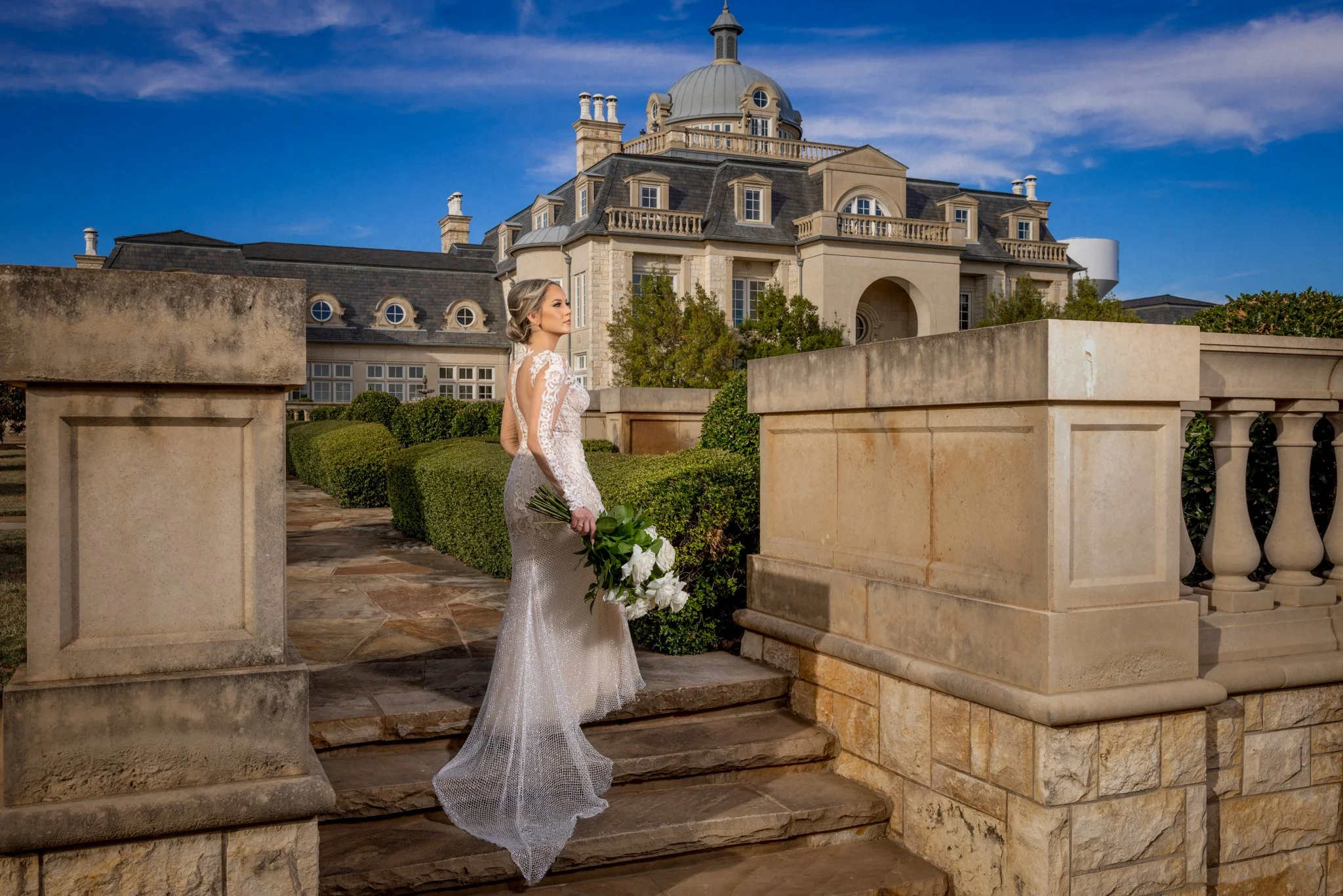 Bride holding a white and green wedding bouquet at a luxury wedding venue.