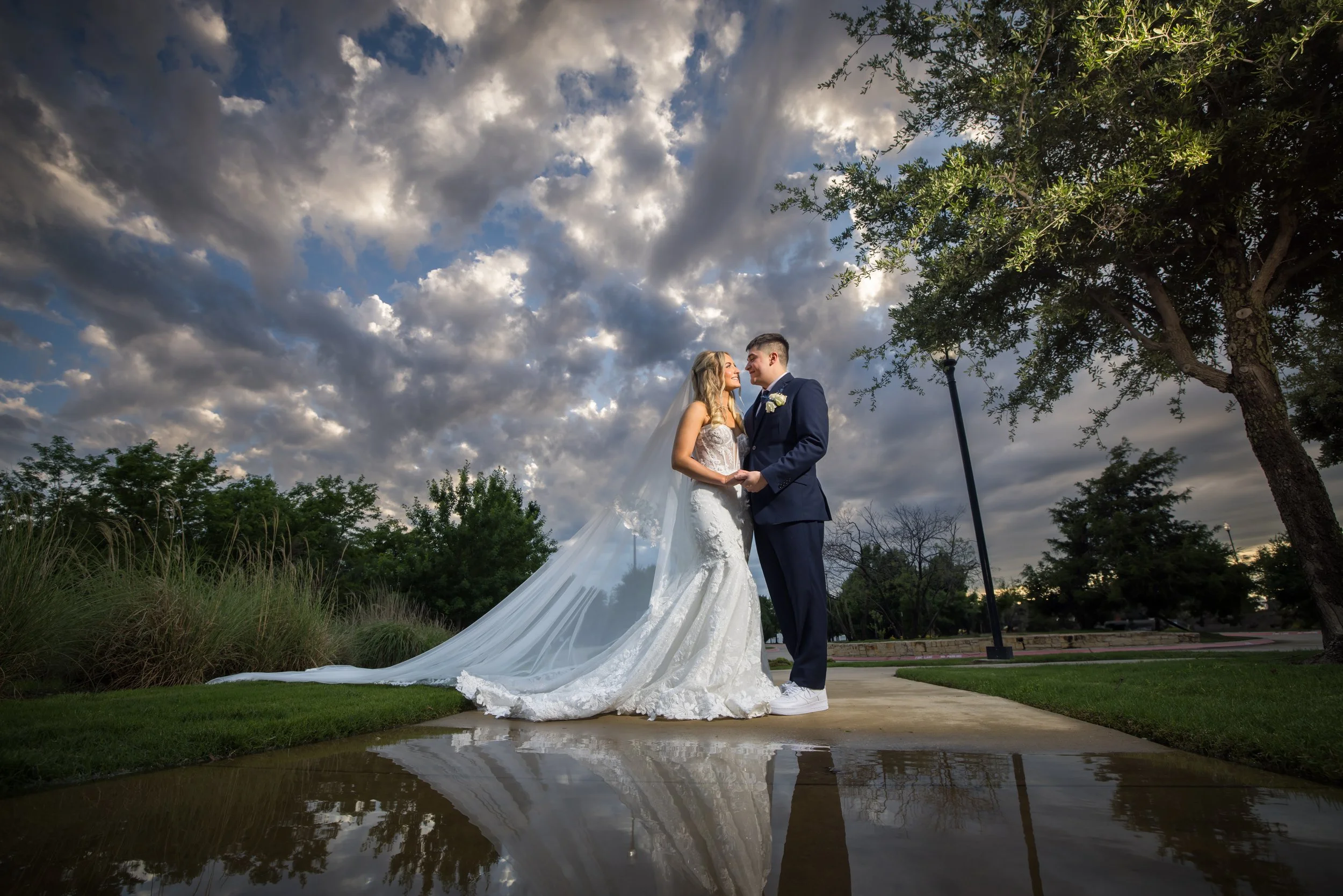 Bride and groom photographed outdoors after rain under dramatic clouds in Dallas–Fort Worth