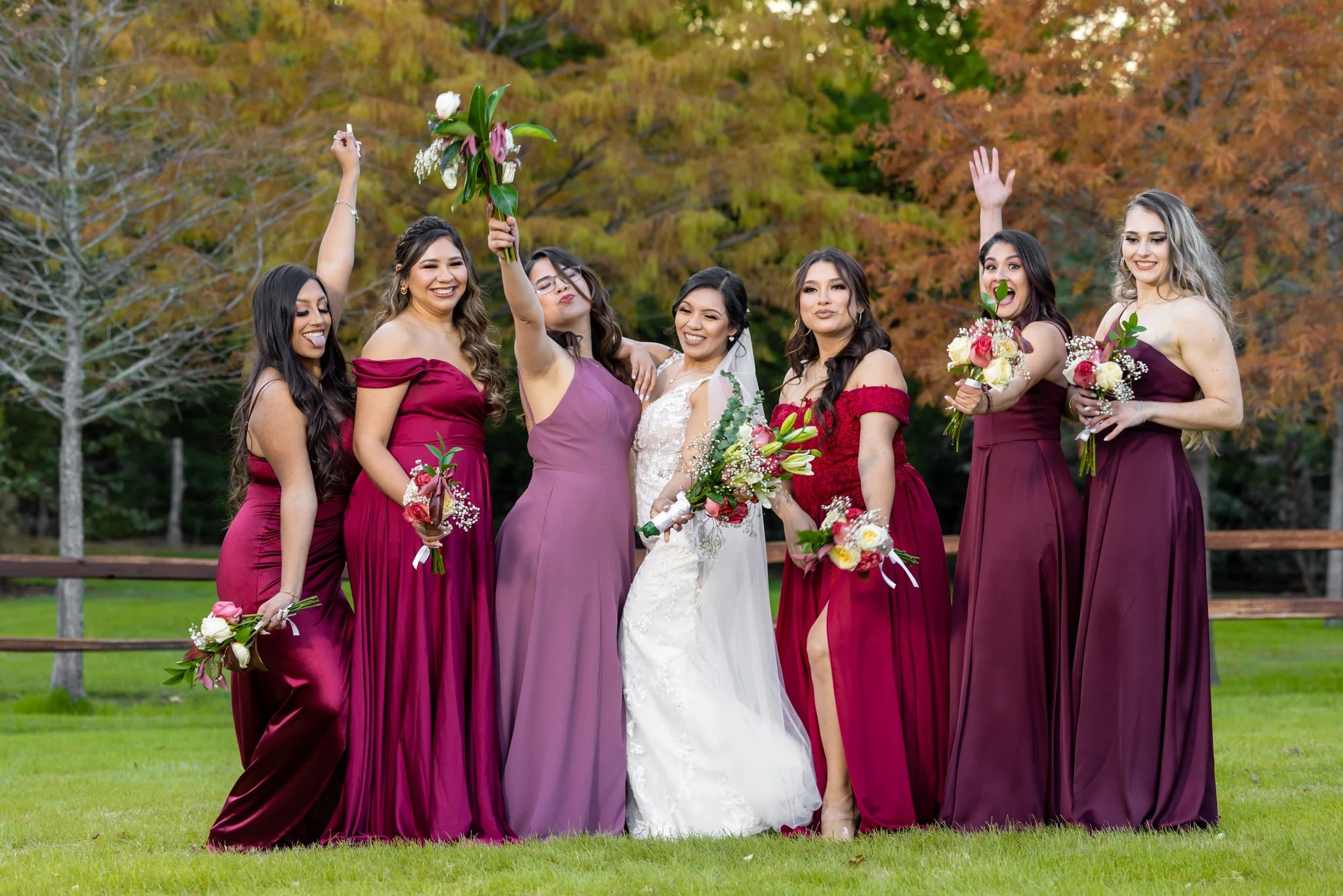 Bride and bridesmaids holding colorful wedding bouquets outdoors.
