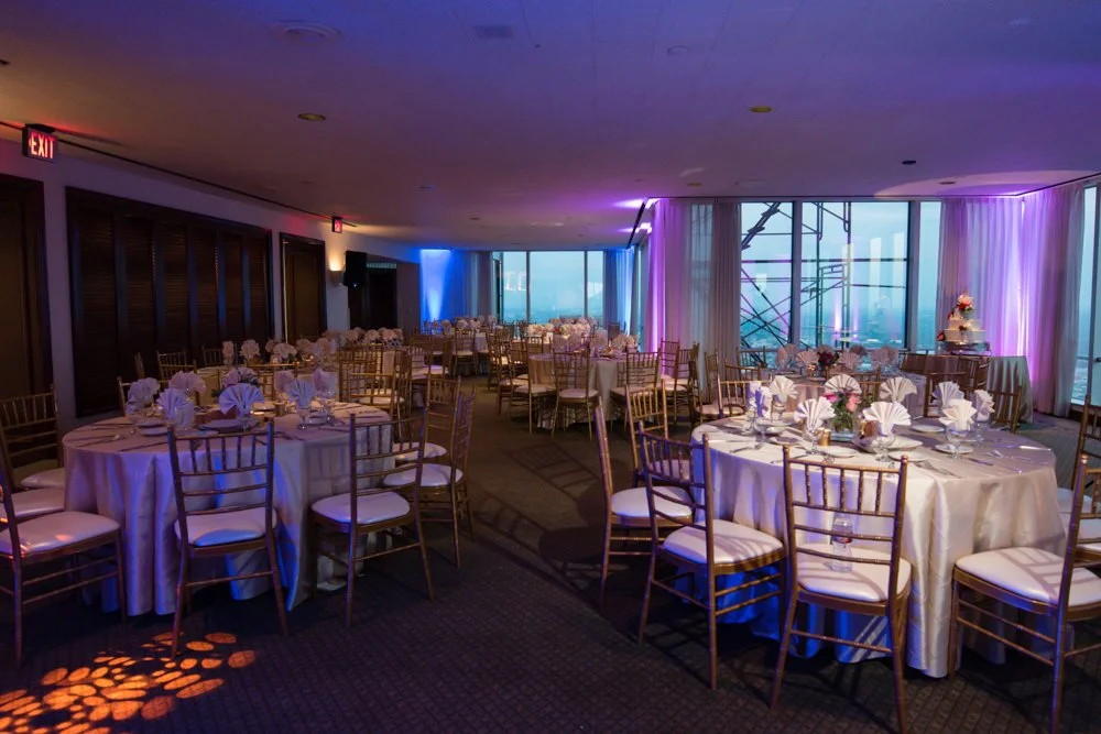 Wedding reception setup with round tables and city views inside Tower Club Dallas in Dallas, Texas.