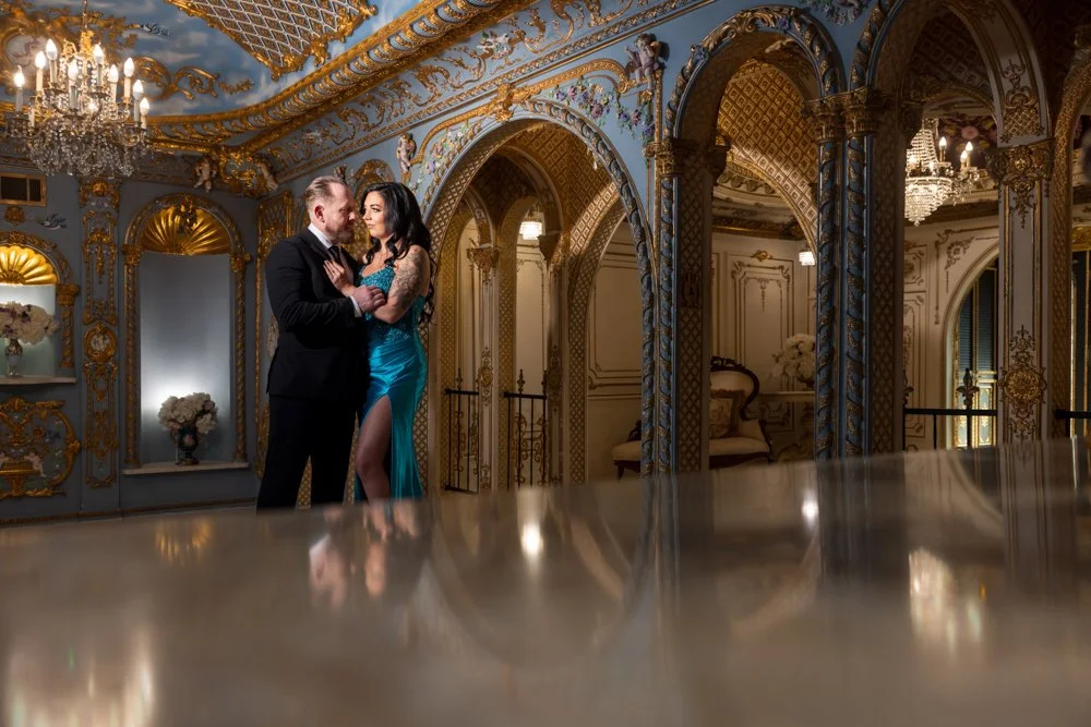 Couple in a blue-and-gold room with their reflection visible on a foreground surface.