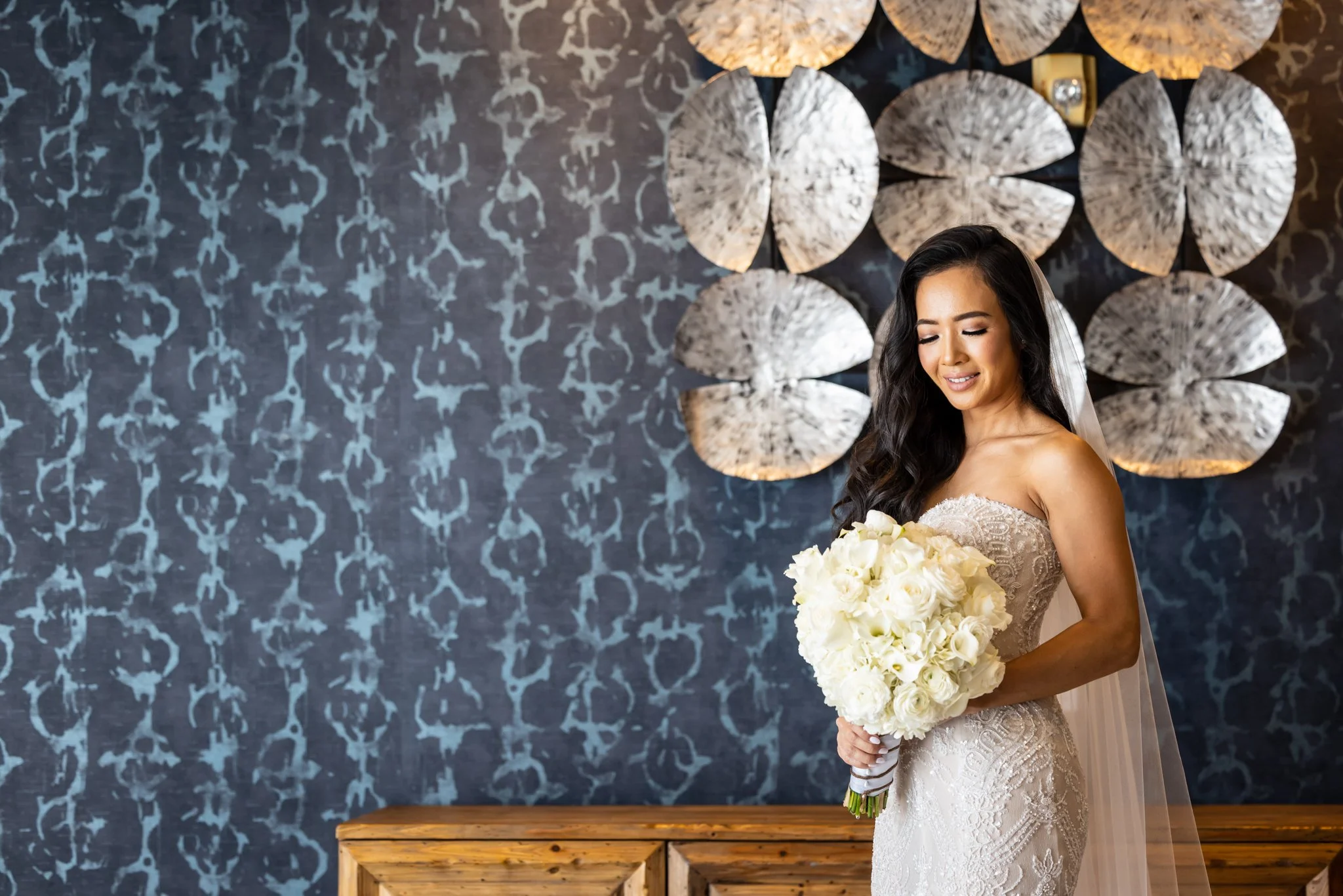 Bride holding a full white wedding bouquet indoors.
