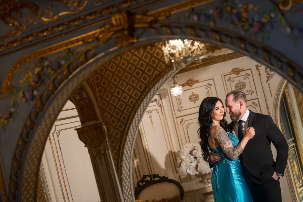 Angled portrait of a couple with decorated arches and ceiling details surrounding them.