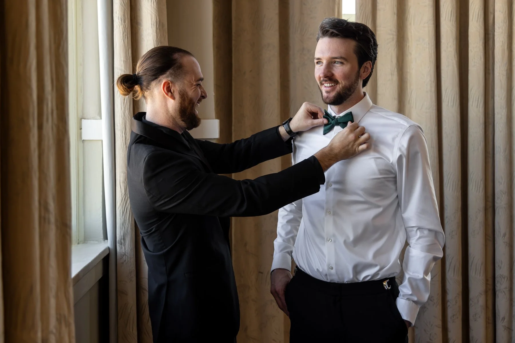 Groom having his bow tie adjusted while getting ready for his wedding at The Room on Main in Dallas