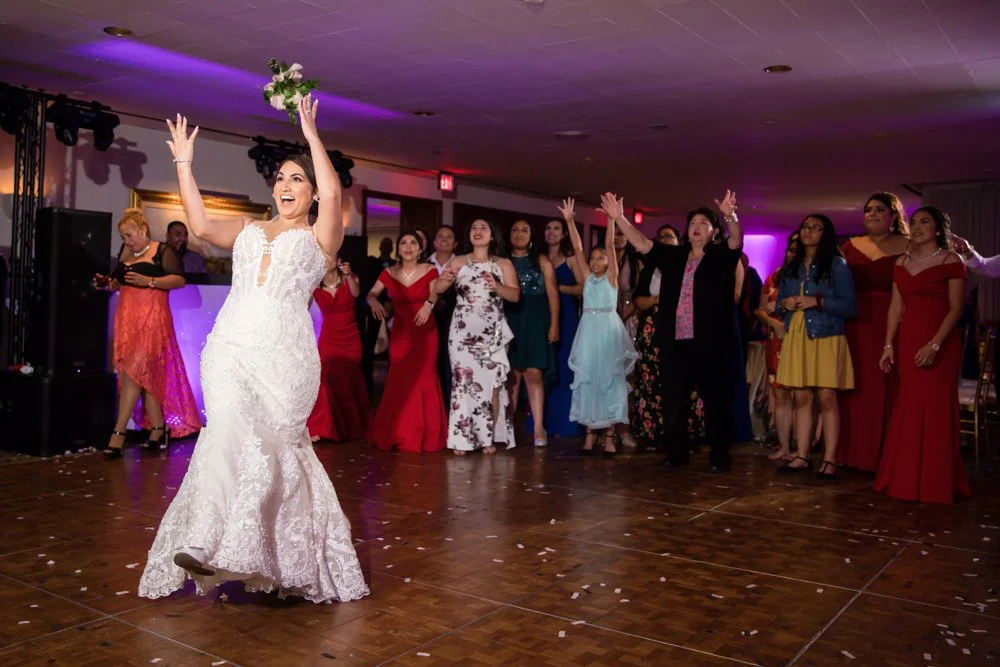 Bride tossing her bouquet to wedding guests during a reception at Tower Club Dallas in Dallas, Texas.