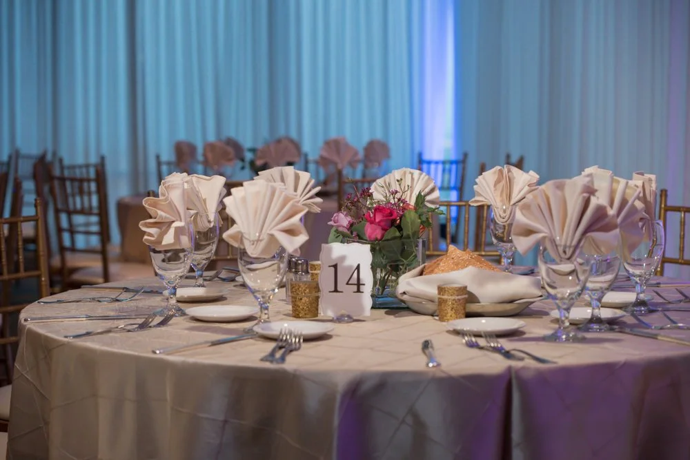 Elegant wedding reception table with folded napkins, glassware, floral centerpiece, and table number 14 at Tower Club Dallas.
