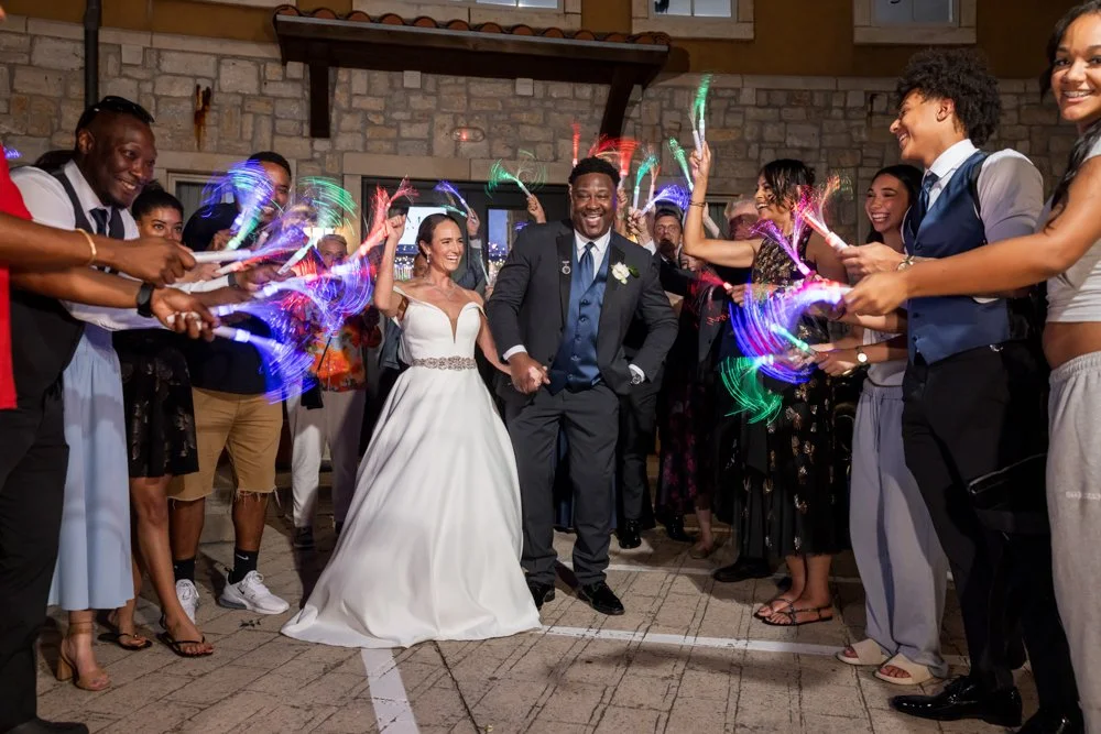 Mallory and Marcus leaving their reception as guests wave glowing lights.