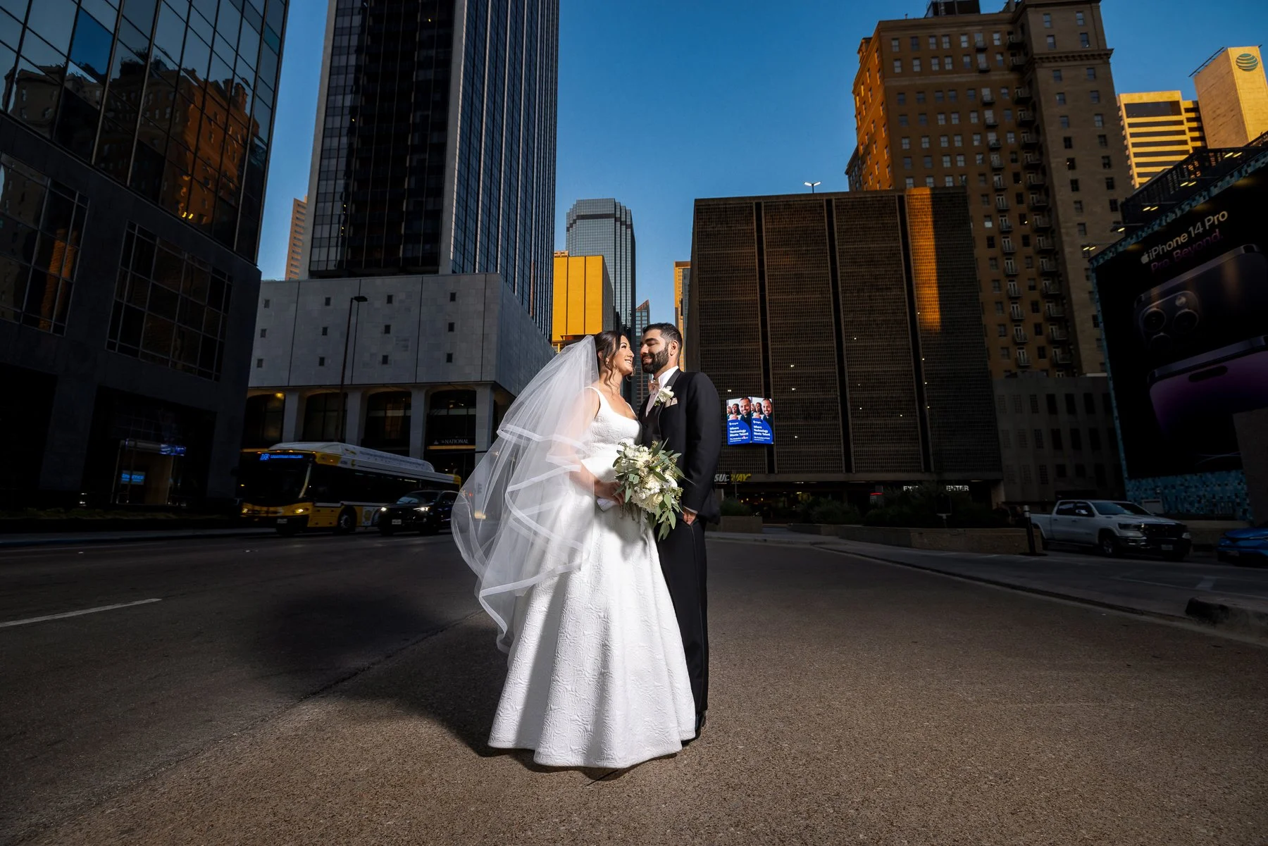 Bride and groom wedding portrait with flowing veil and Dallas skyline at The Westin Dallas Downtown