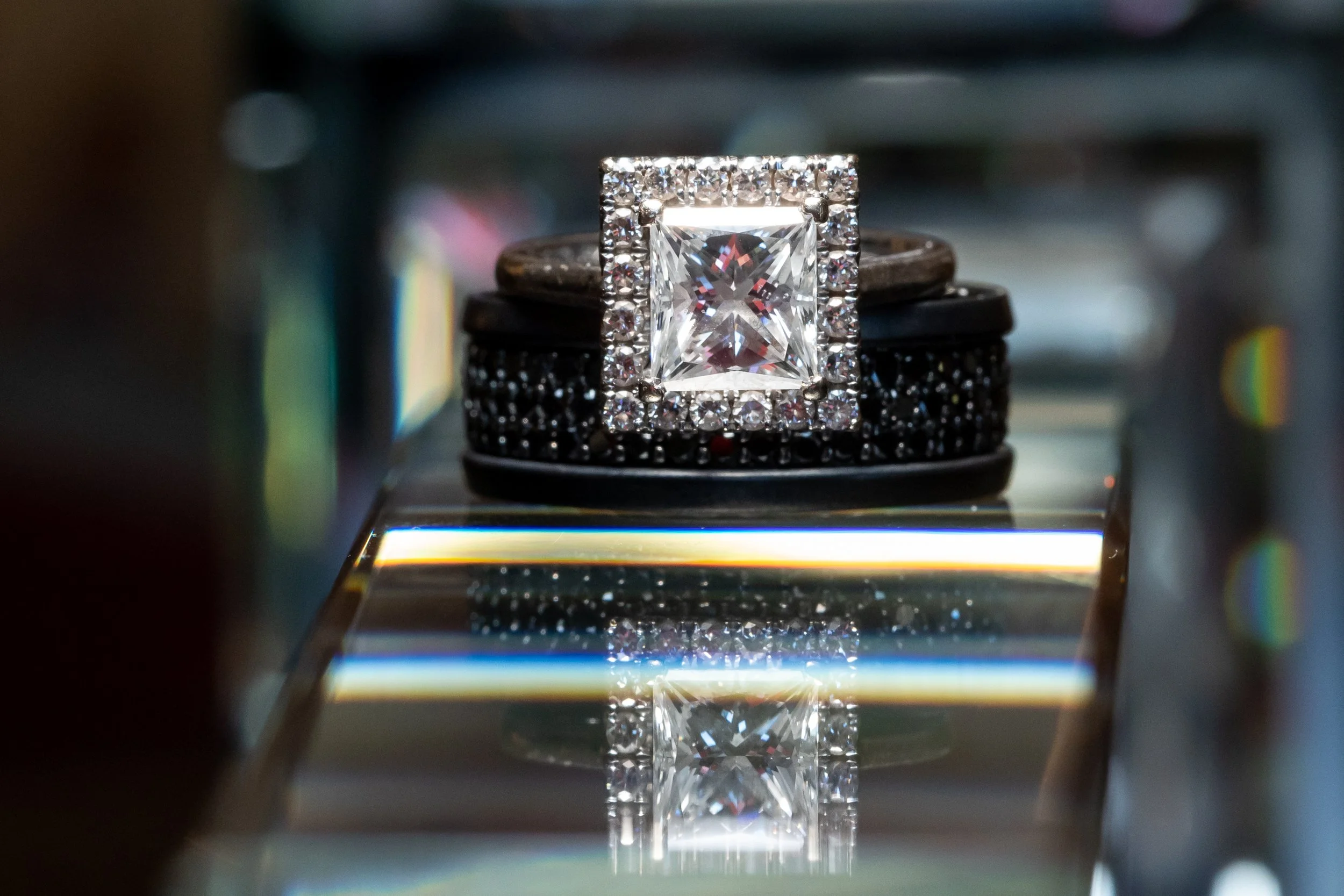 Princess-cut diamond engagement ring paired with a black wedding band.