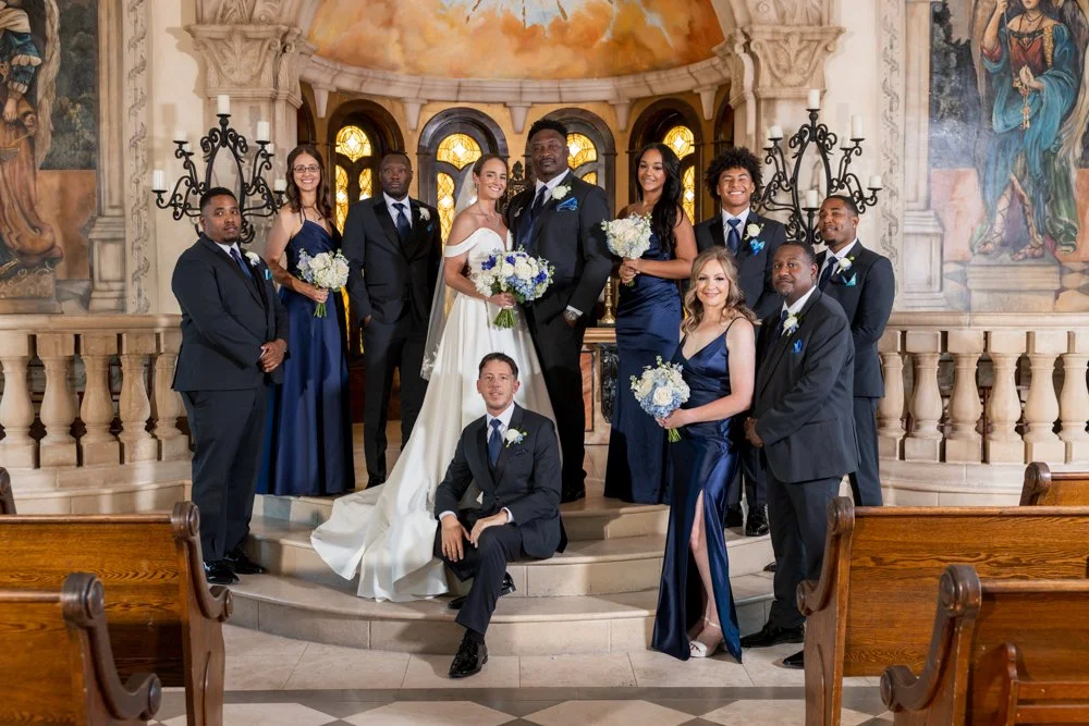 Mallory and Marcus with their wedding party in blue attire inside the chapel.