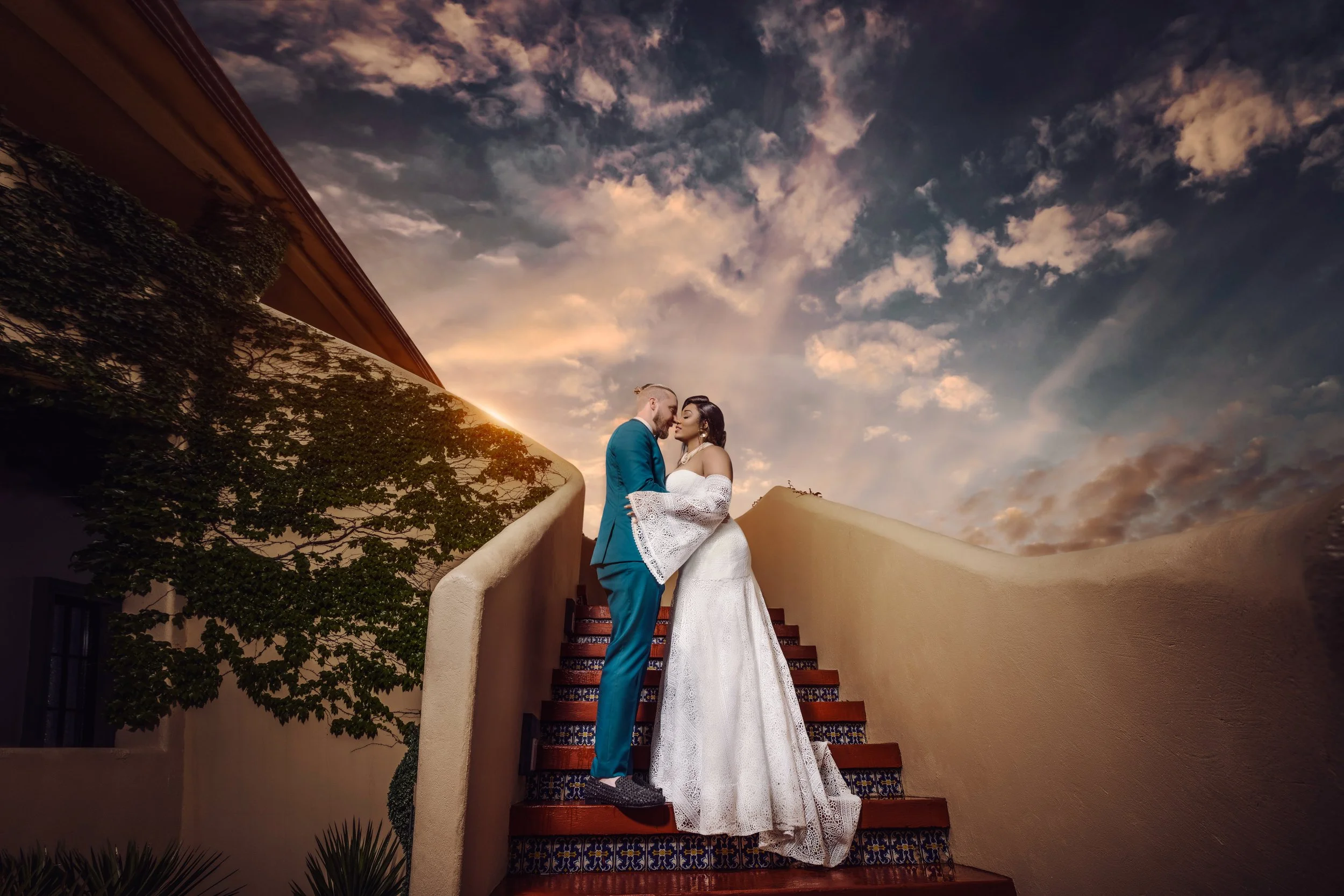 Bride and groom kissing on an outdoor staircase during a cinematic wedding portrait session.