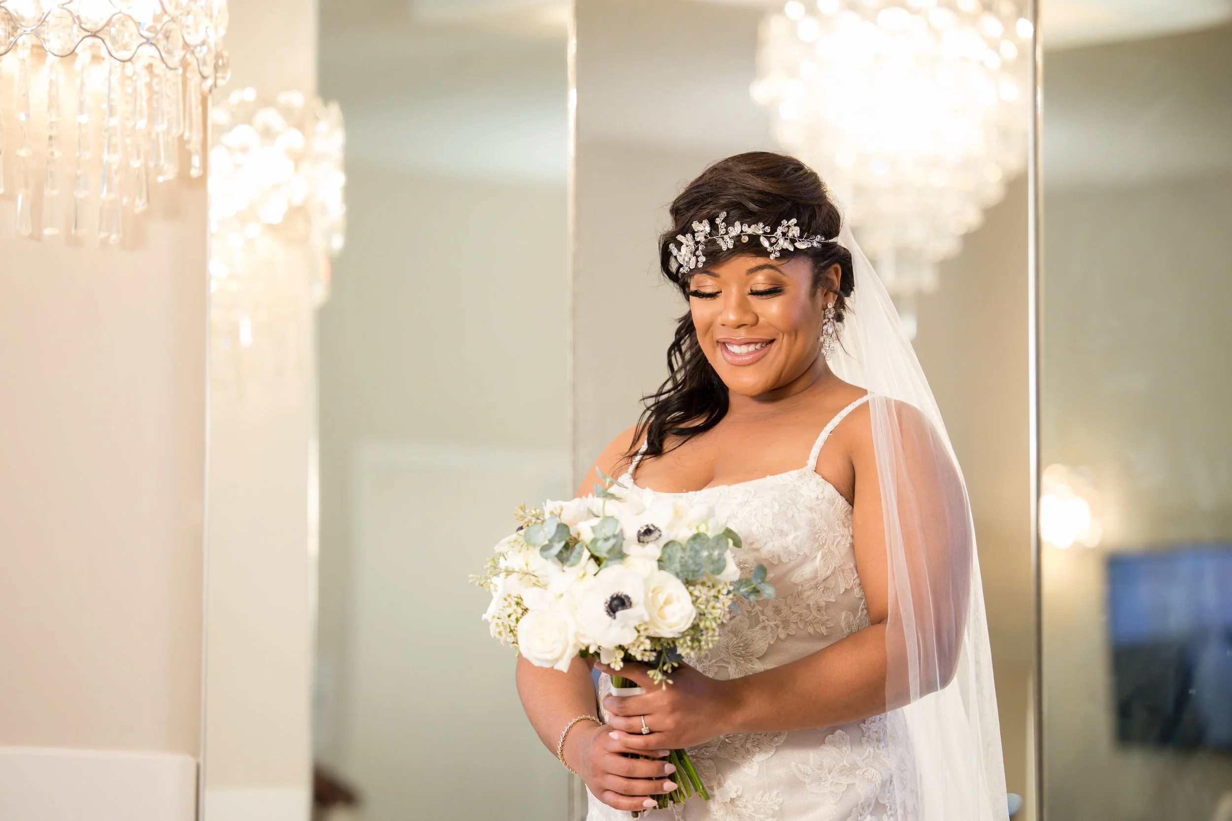 Bride holding a white wedding bouquet with greenery.