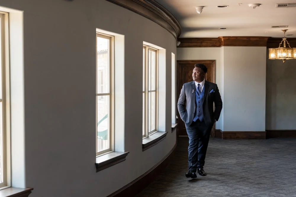 Marcus in blue wedding attire beside the windows while getting ready at The Sanctuary.
