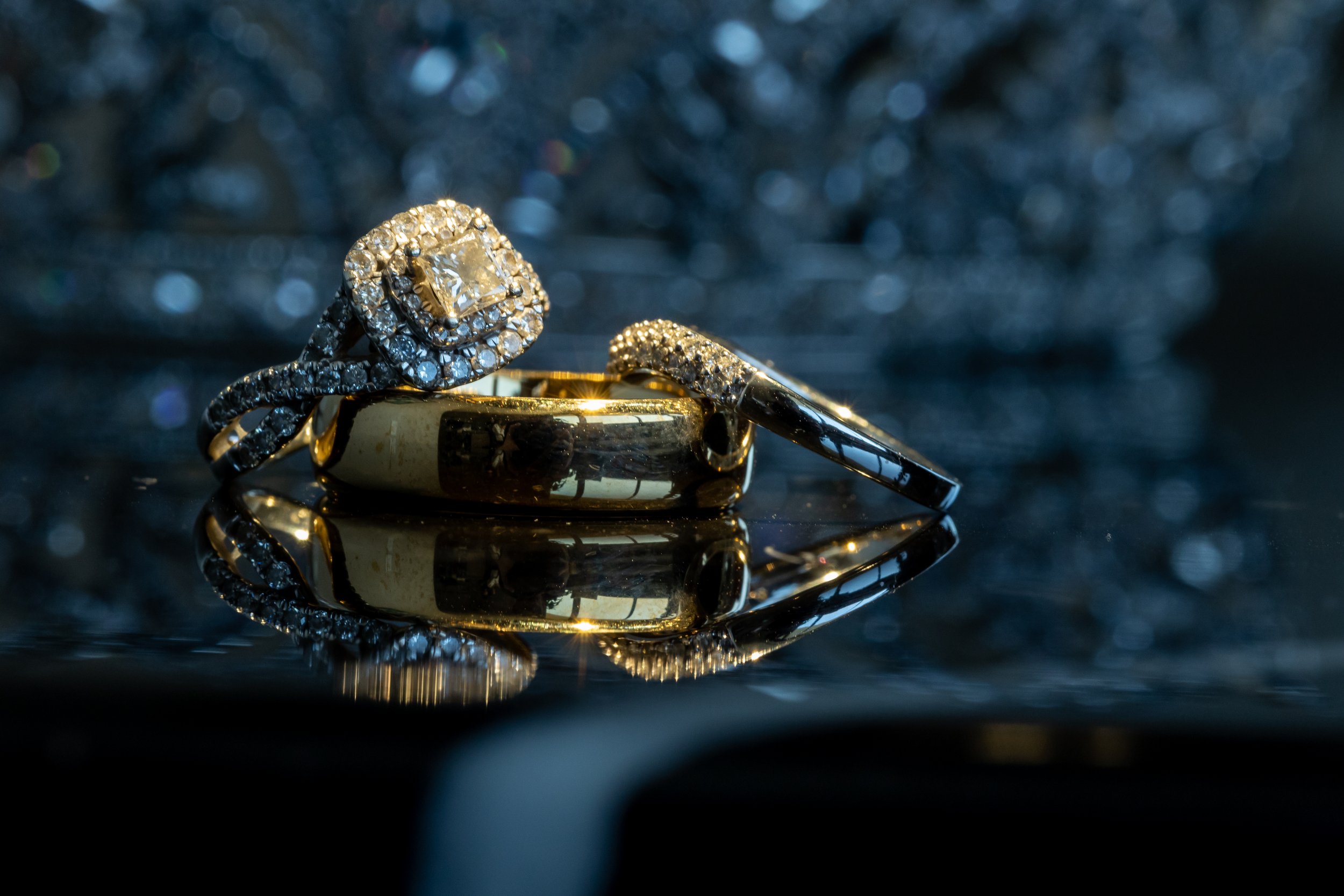 Wedding rings and engagement rings arranged together in a close-up detail photograph.
