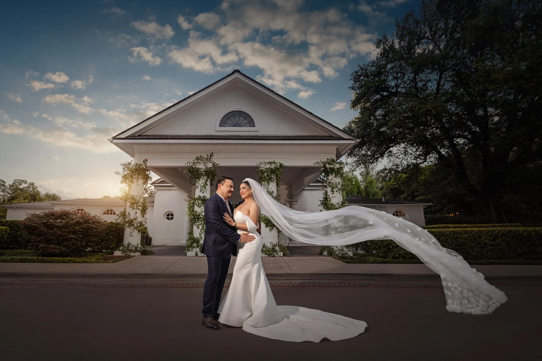 Bride and groom portrait outside Arlington Hall at Turtle Creek in Dallas with the bride’s veil flowing behind them.