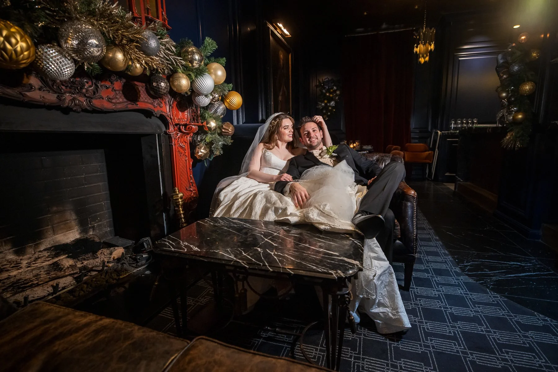 Bride and groom relaxing beside the fireplace during their wedding at The Adolphus Hotel in Dallas