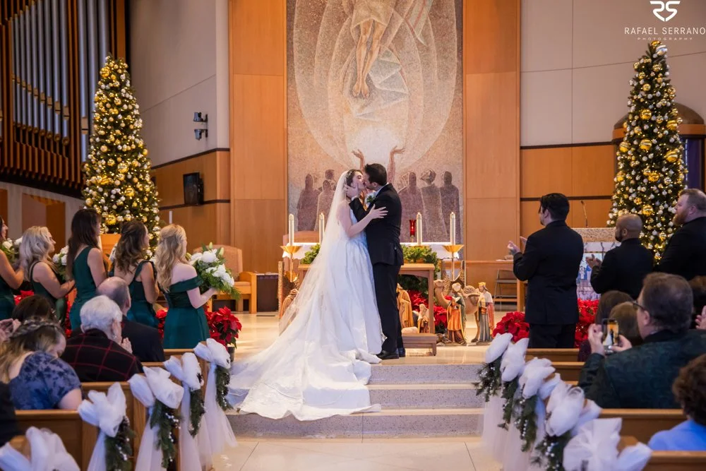 McKenna and Chris kissing at the front of St. Monica as guests applaud.