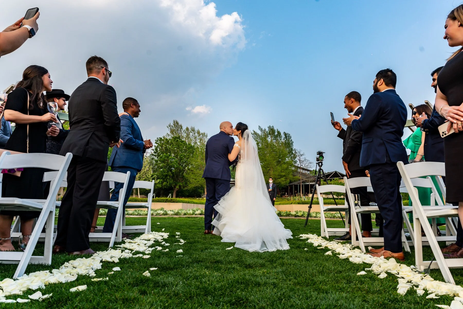 Bride and groom during their outdoor wedding ceremony surrounded by gardens at the Dallas Arboretum in Dallas.
