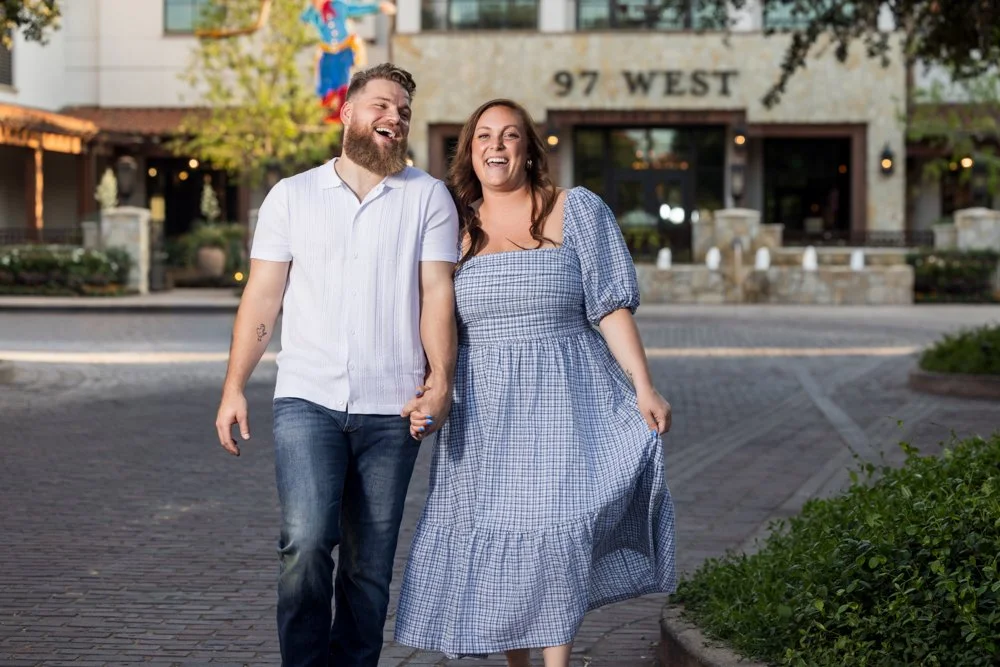 Lacey and Trey laughing while walking hand in hand outside 97 West at Hotel Drover.