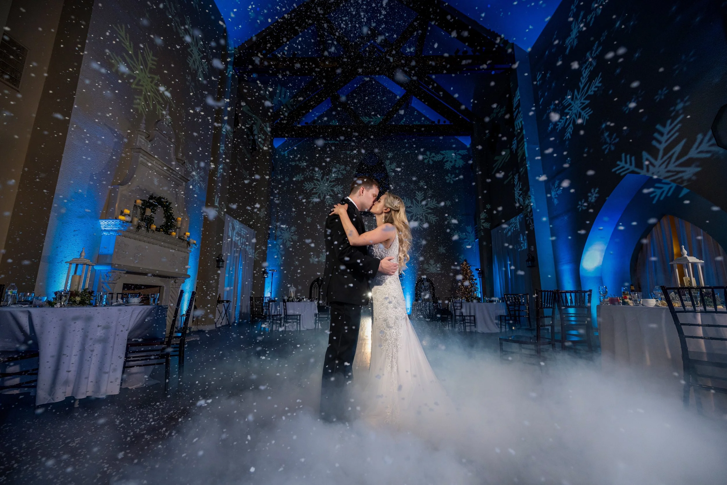 Bride and groom sharing a first dance surrounded by falling snow.
