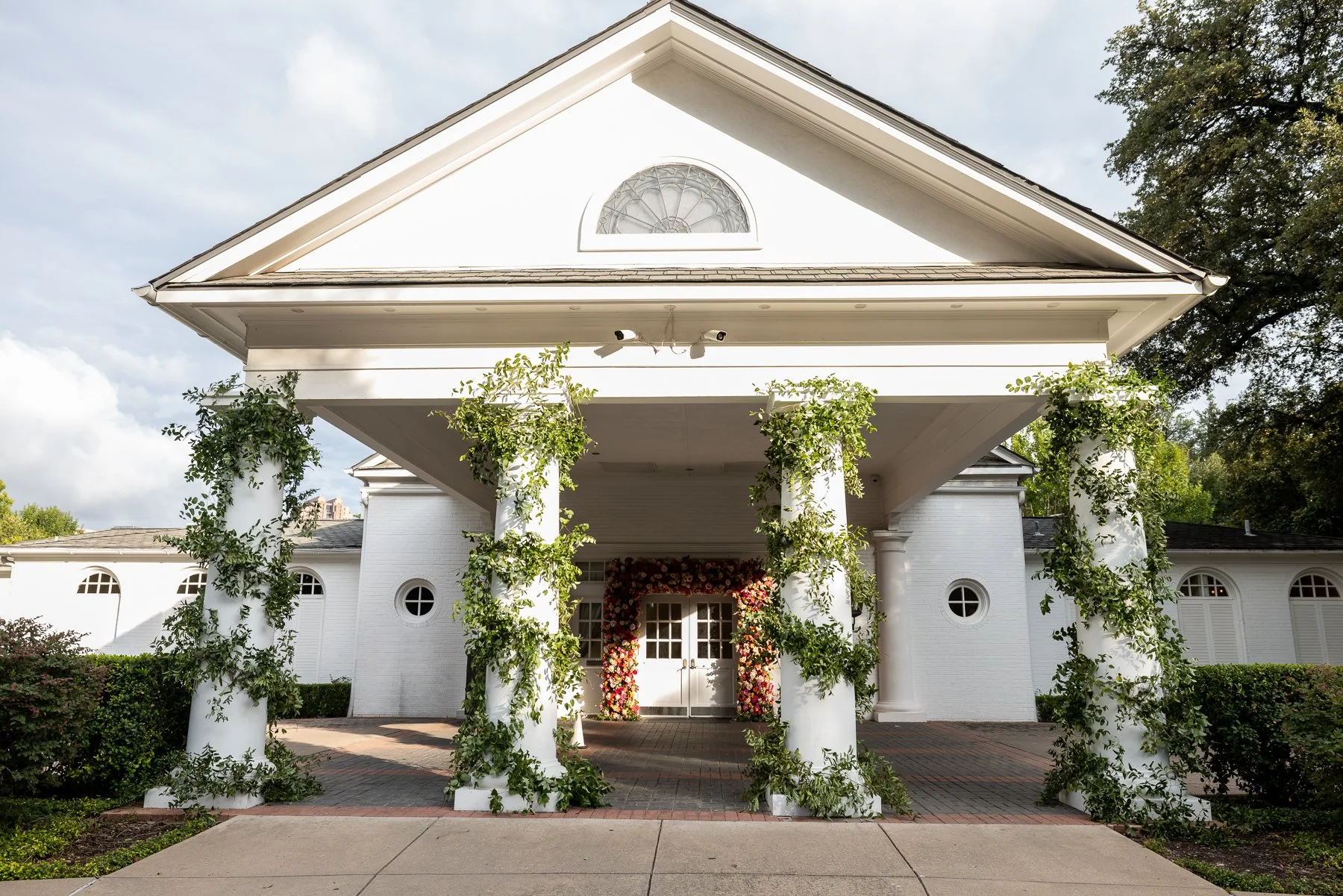 Exterior of Arlington Hall at Turtle Creek in Dallas surrounded by greenery and wedding florals.