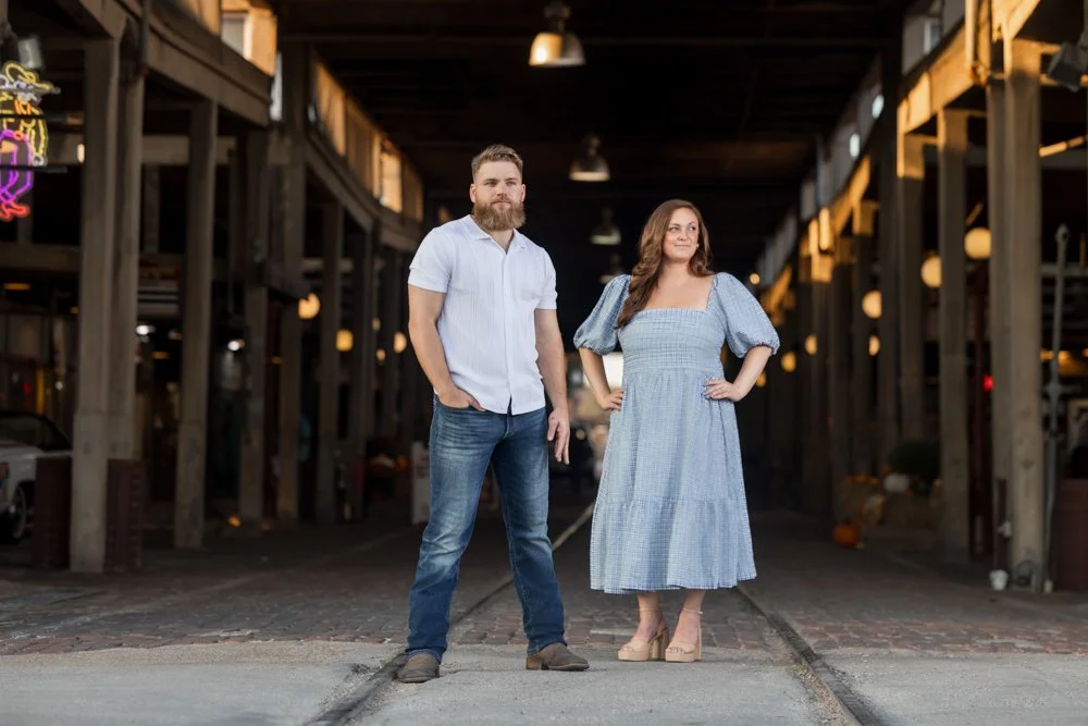 Lacey and Trey holding hands in a full-length portrait framed by a covered wooden passage.