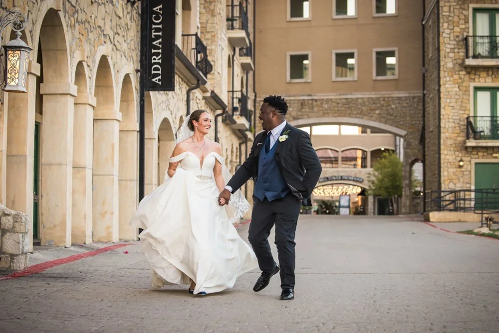 Mallory and Marcus walking hand in hand beneath the Adriatica sign.