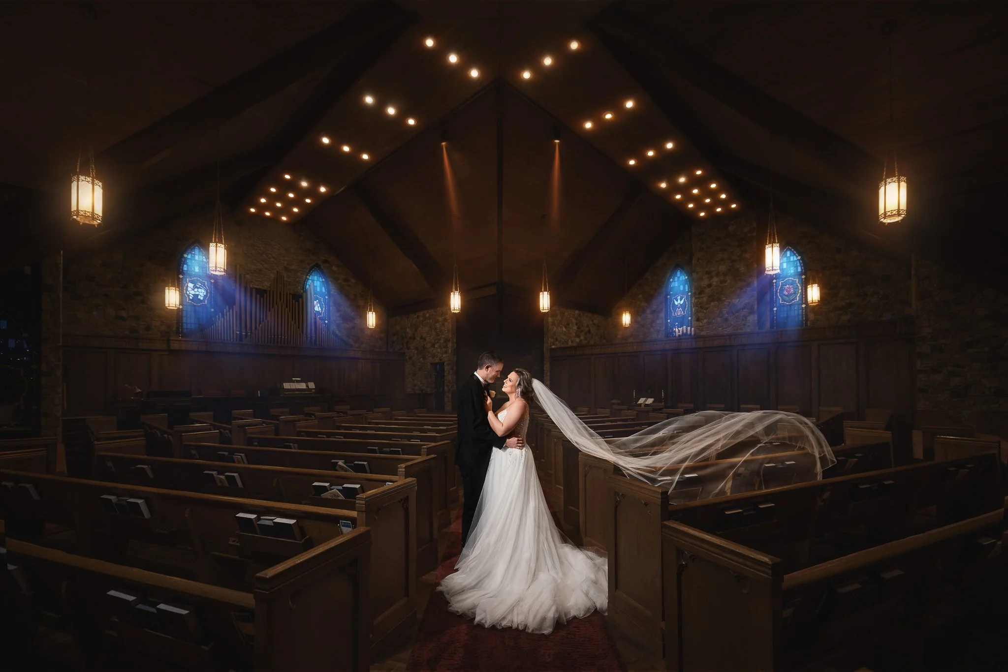 Bride and groom portrait inside an elegant church with dramatic wedding lighting.