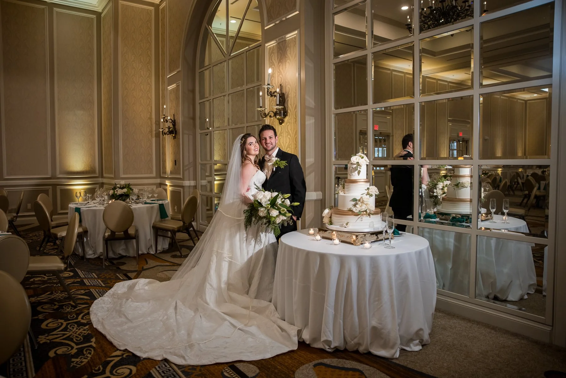 Bride and groom beside their wedding cake during their reception at The Adolphus Hotel
