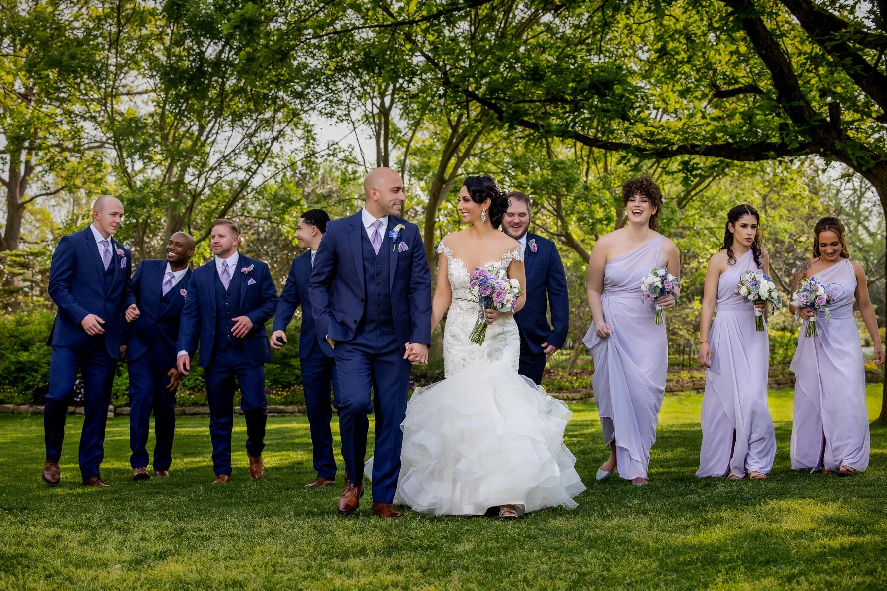 Bride and groom walking with their wedding party through the gardens at the Dallas Arboretum in Dallas.